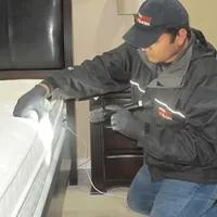Bed bug inspection technician checking a mattress and bed frame for signs of infestation in Richmond, VA